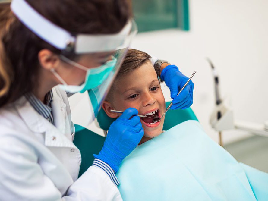 A female dentist checking on a young boys teeth